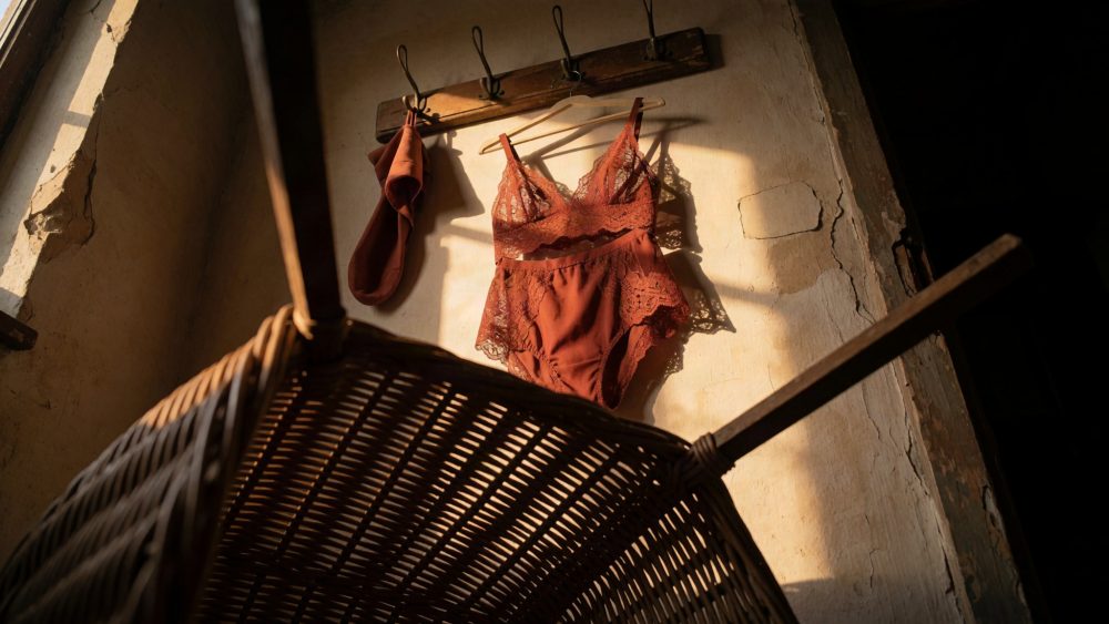 Conjunto de lingerie em renda cor terra pendurado numa parede rústica com iluminação natural
