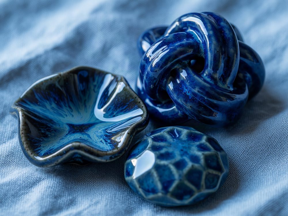 Conjunto de peças cerâmicas azuis brilhantes e orgânicas sobre tecido azul claro