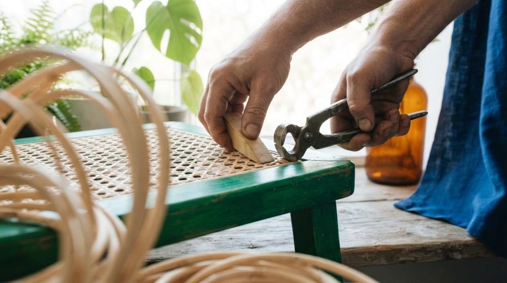 Mãos a restaurar tampo de cadeira em palhinha usando ferramentas de bricolage