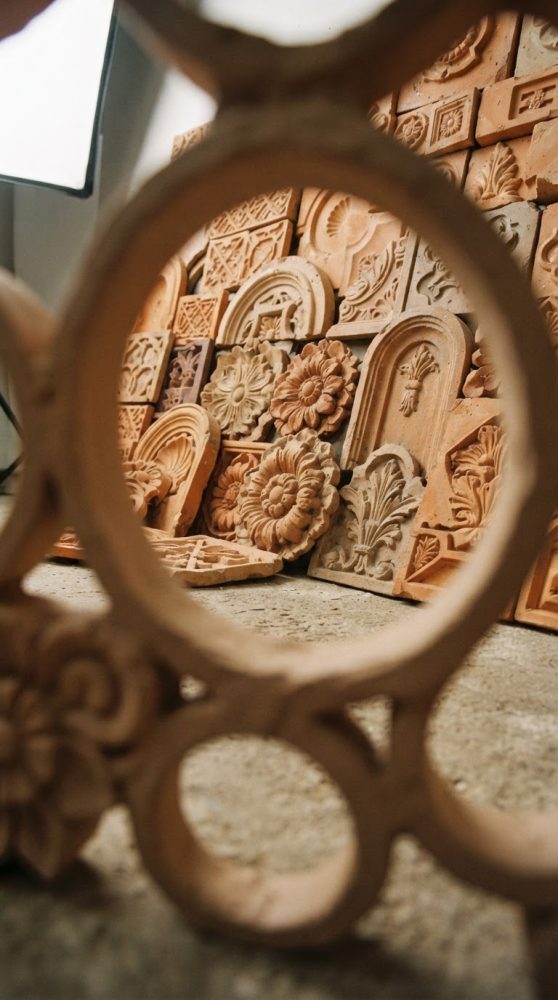 Peças decorativas em cerâmica com formas florais e geométricas vistas através de moldura circular