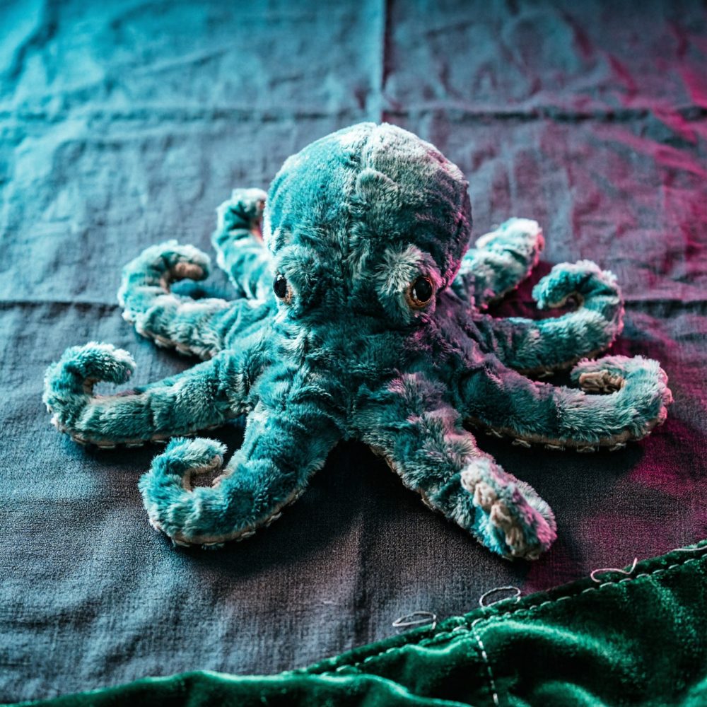Polvo de peluche azul macio sobre tecido escuro com iluminação suave colorida