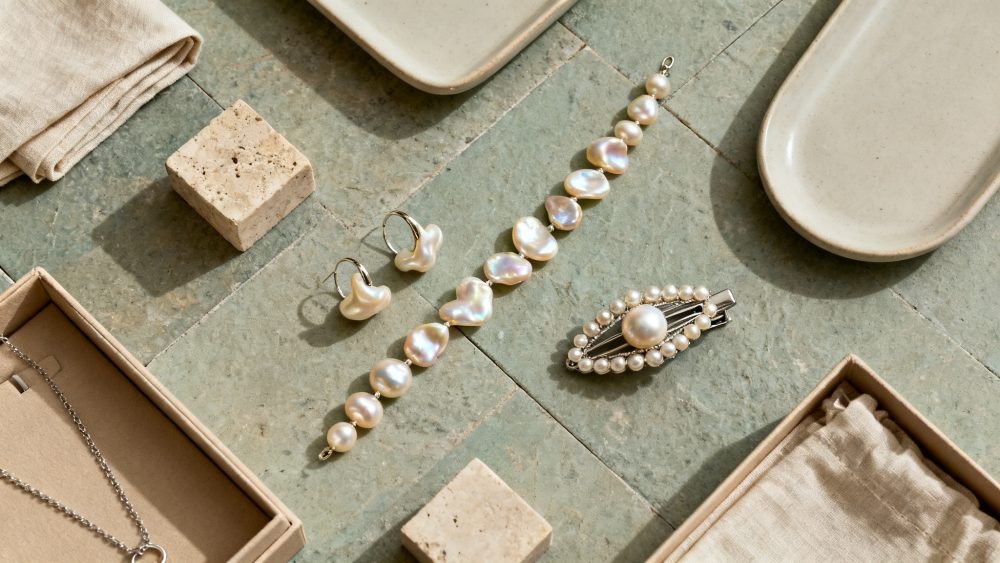 Conjunto de brincos, pulseira e presilha com pérolas naturais em superfície de pedra