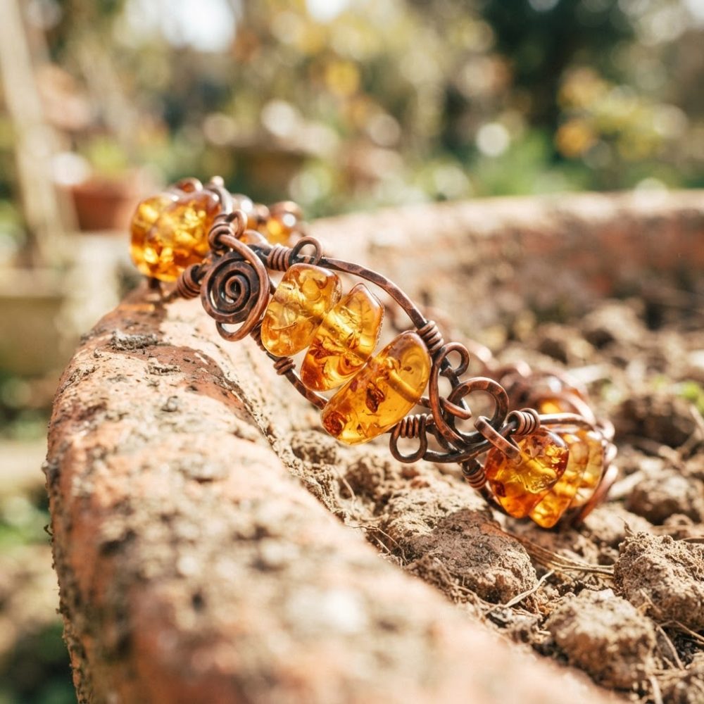 Pulseira artesanal com pedras âmbar em fios de cobre sobre superfície terrosa