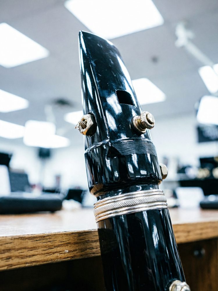 Bocal de clarinete com palheta presa sobre mesa de madeira em loja de música