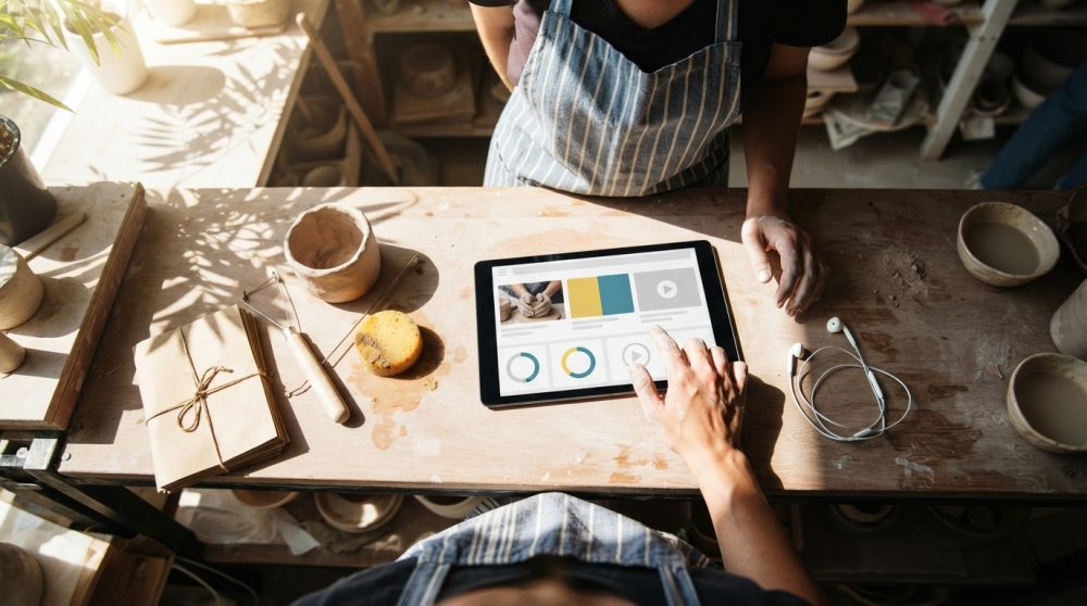 Duas pessoas num ateliê de cerâmica a usar um tablet para aceder a conteúdos digitais