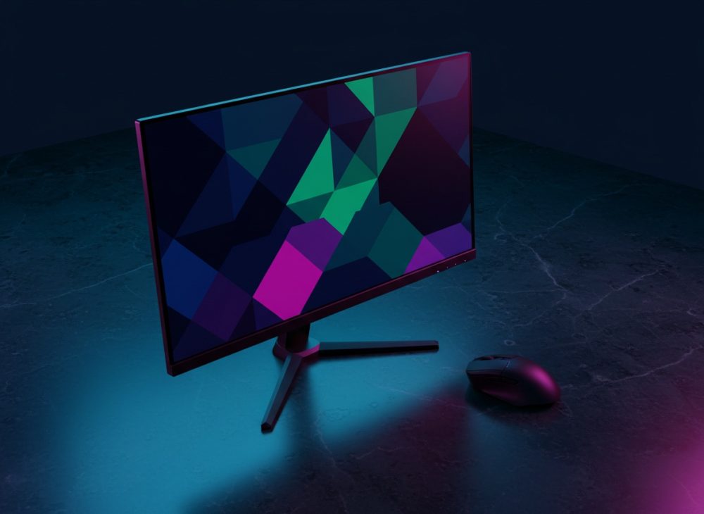 Monitor gaming com design moderno ao lado de rato sobre mesa escura com iluminação azul e violeta