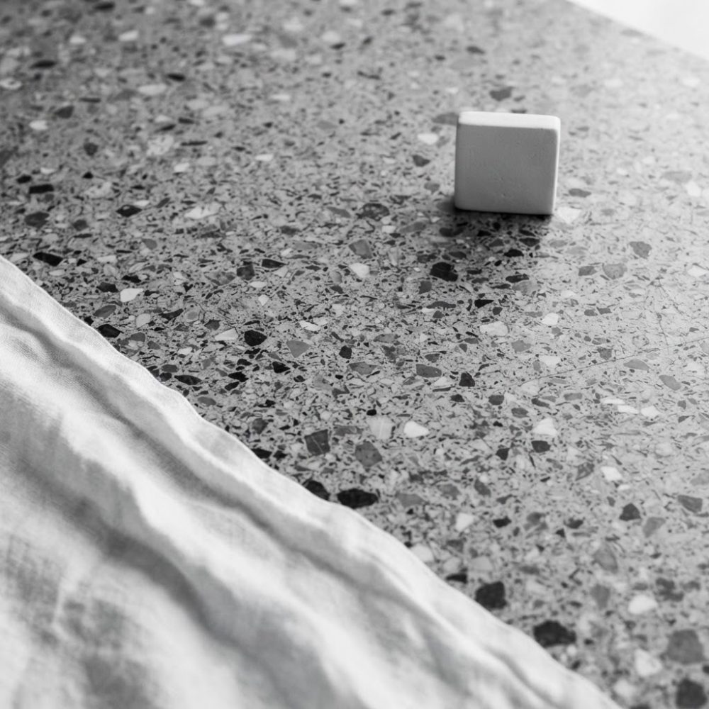 Superfície de pedra terrazzo com textura, pano branco e cubo branco
