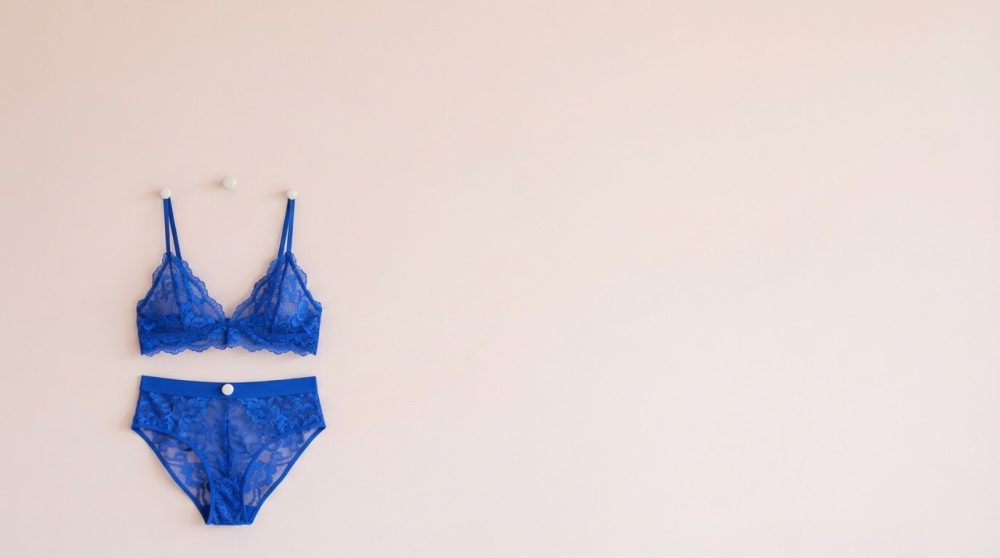 Conjunto de lingerie azul rendado pendurado numa parede clara