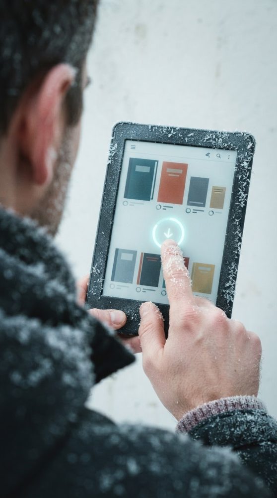 Pessoa com tablet coberto de neve a descarregar livros digitais no ecrã