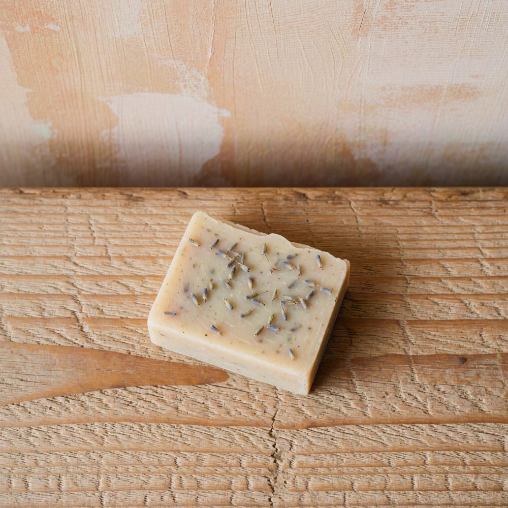Sabonete artesanal creme com flores secas de lavanda sobre madeira envelhecida
