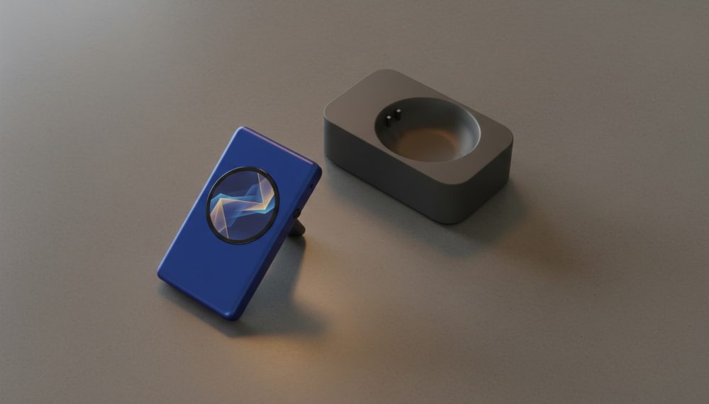 Dispositivo portátil azul inclinado ao lado de uma base de carga preta sobre superfície cinzenta.