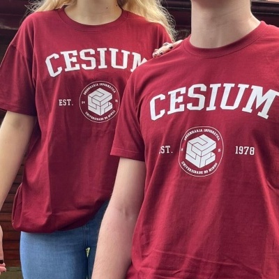 Duas pessoas com t-shirts vermelhas CESIUM com selo e texto em branco ao ar livre