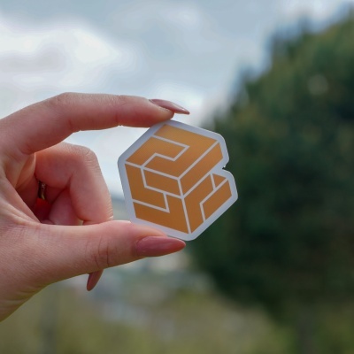 Mão segurando autocolante translúcido com padrão geométrico amarelo