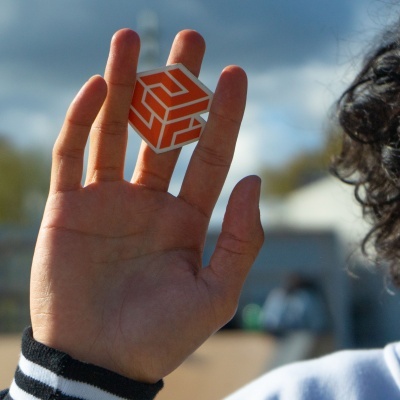 Mão segurando cubo com padrão geométrico laranja e branco