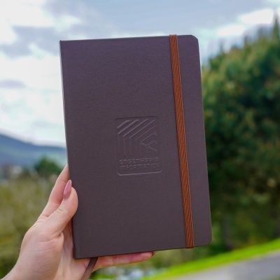 Caderno castanho com elástico segurado na mão em ambiente exterior