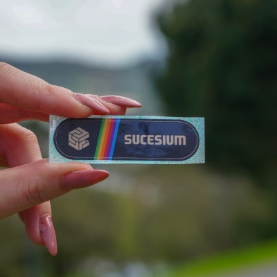 Autocolante holográfico com texto SUCESIUM e faixa arco-íris