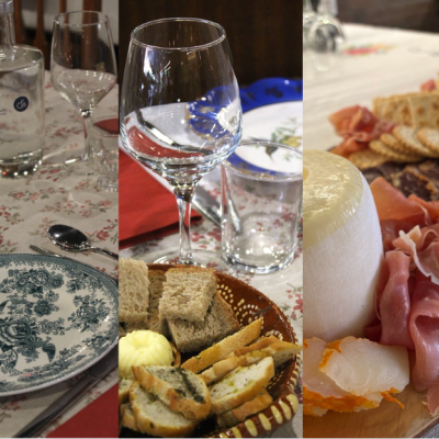 Mesa com pratos, taças, copos e tábuas de queijos e charcutaria para refeição.