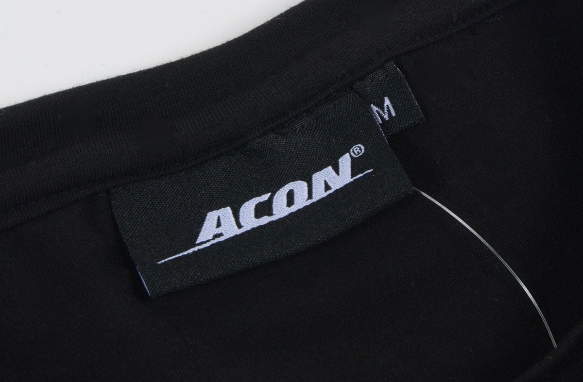 Etiqueta preta com logo ACON e tamanho M numa peça de roupa preta
