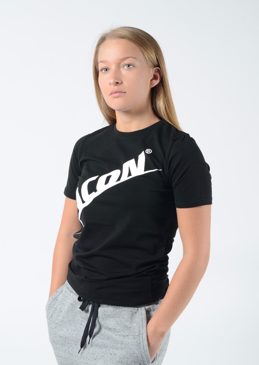 Mulher com t-shirt preta ICON e calças cinzentas em fundo branco.