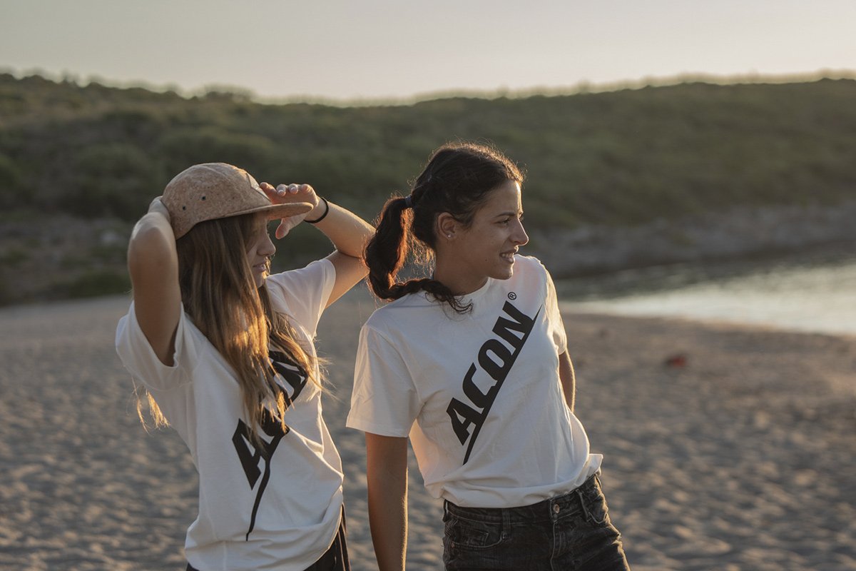 Duas mulheres na praia com t-shirts brancas ACΝ