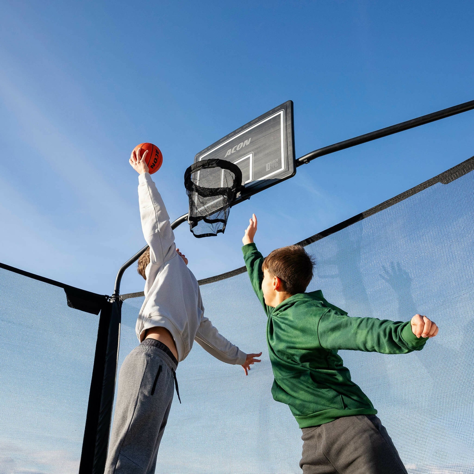 Cesto de basquetebol ACON preto com rede e duas crianças a jogar ao ar livre