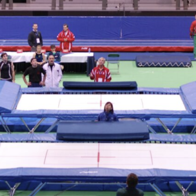Trampolins de competição em ginásio com pessoas a observar
