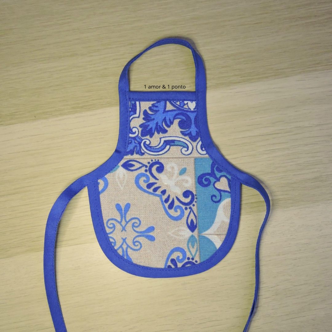 Avental pequeno em tecido com padrão azul, lilás e bege com etiqueta