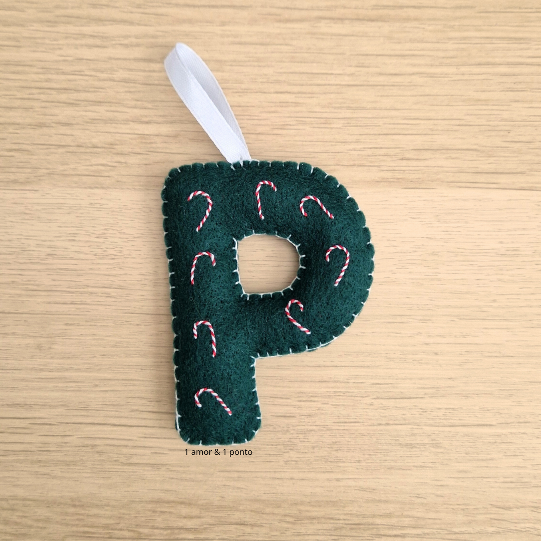 Ornamento de Natal em forma de letra P em tecido verde escuro com bordados vermelhos e brancos.