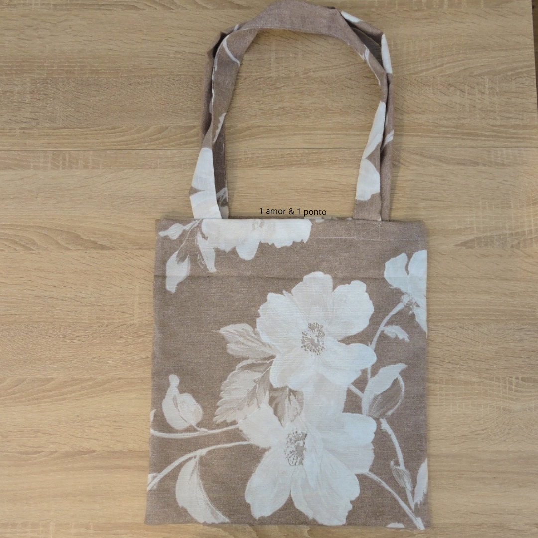 Saco de tecido floral castanho e branco com texto '1 amor & 1 ponto'