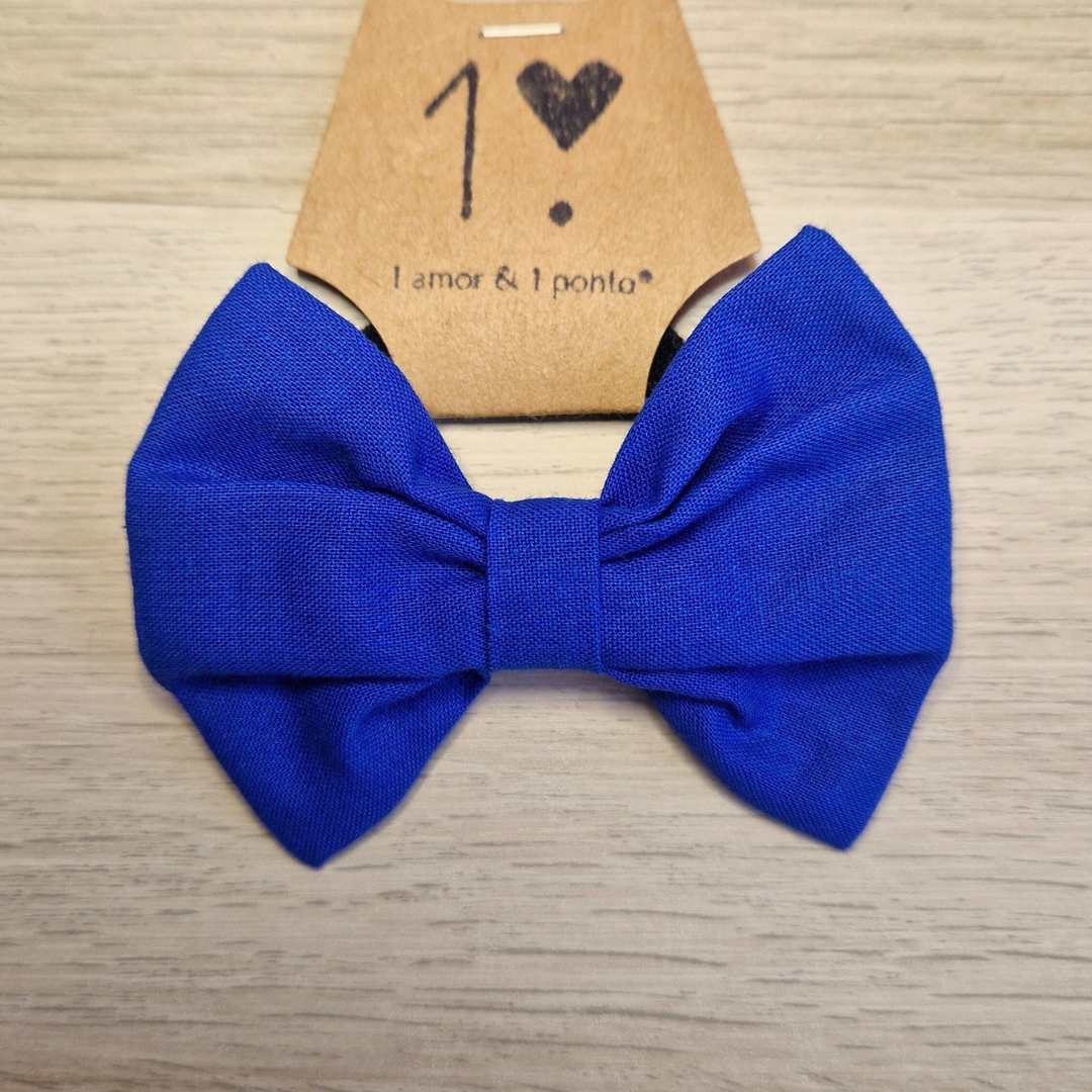 Laço azul em tecido com cartão castanho e texto, sobre mesa de madeira clara