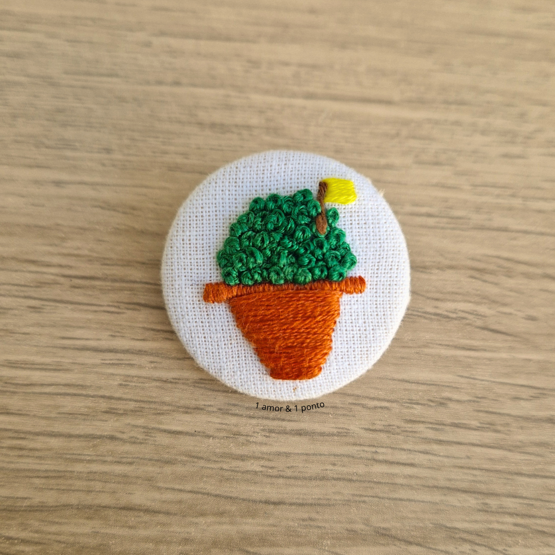Botão bordado com vaso de planta colorida em tecido branco