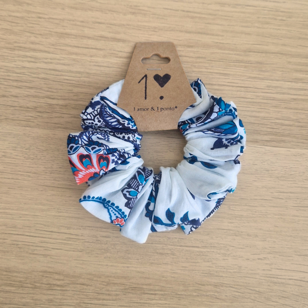 Elástico de cabelo scrunchie com padrão floral azul, branco e vermelho e etiqueta com texto '1 amor & 1 portão'