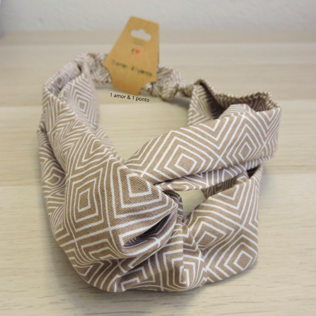 Turbante de tecido beige com padrão geométrico de losangos em branco com etiqueta