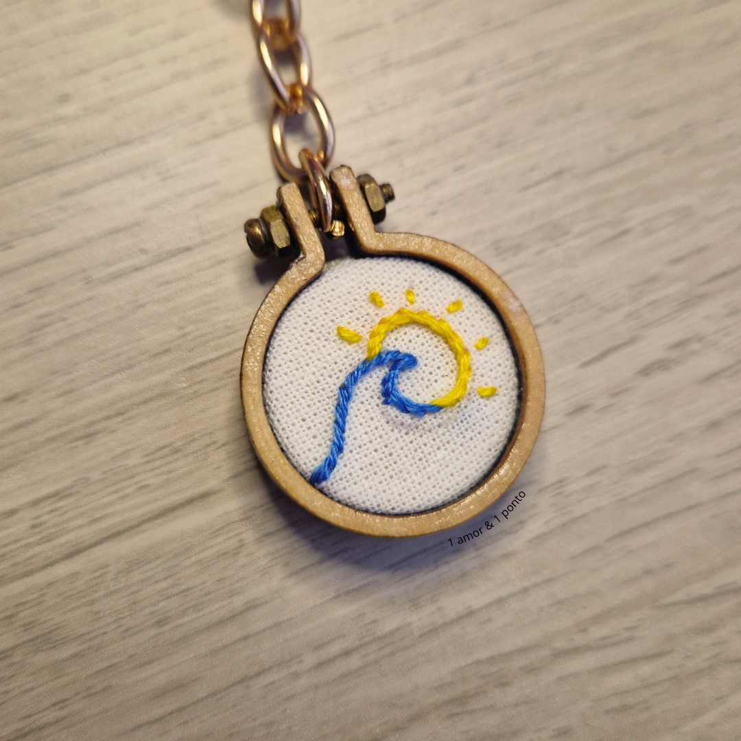 Chaveiro bordado com desenho de sol e onda em madeira clara com corrente dourada