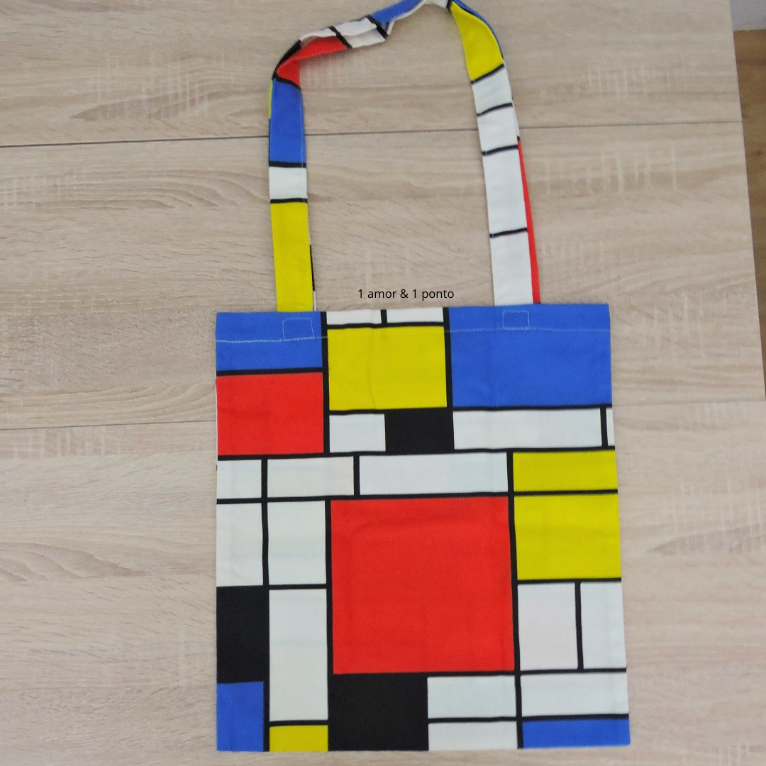 Mala de tecido com padrão geométrico colorido em azul, vermelho, amarelo, branco e preto