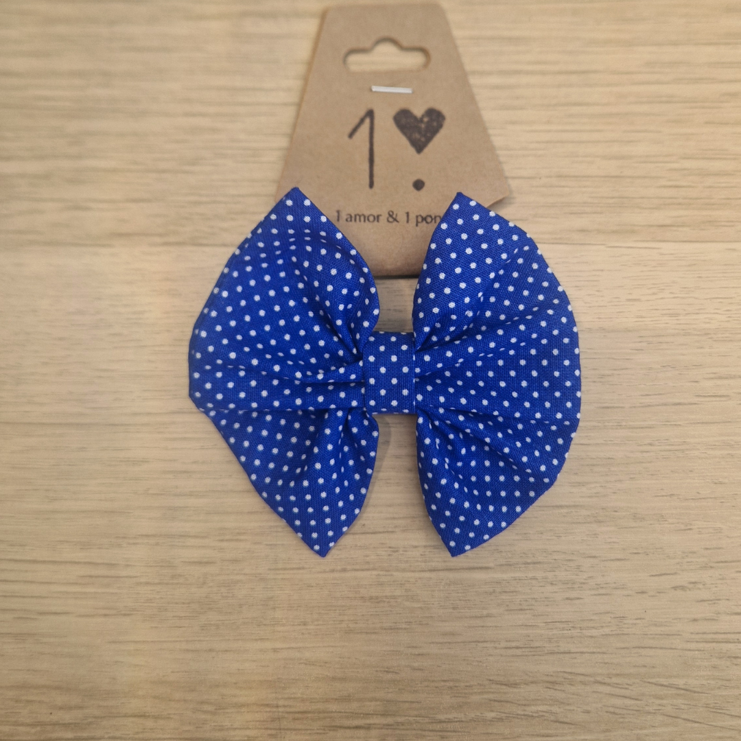 Laço azul com bolinhas brancas em cartão castanho sobre fundo de madeira clara