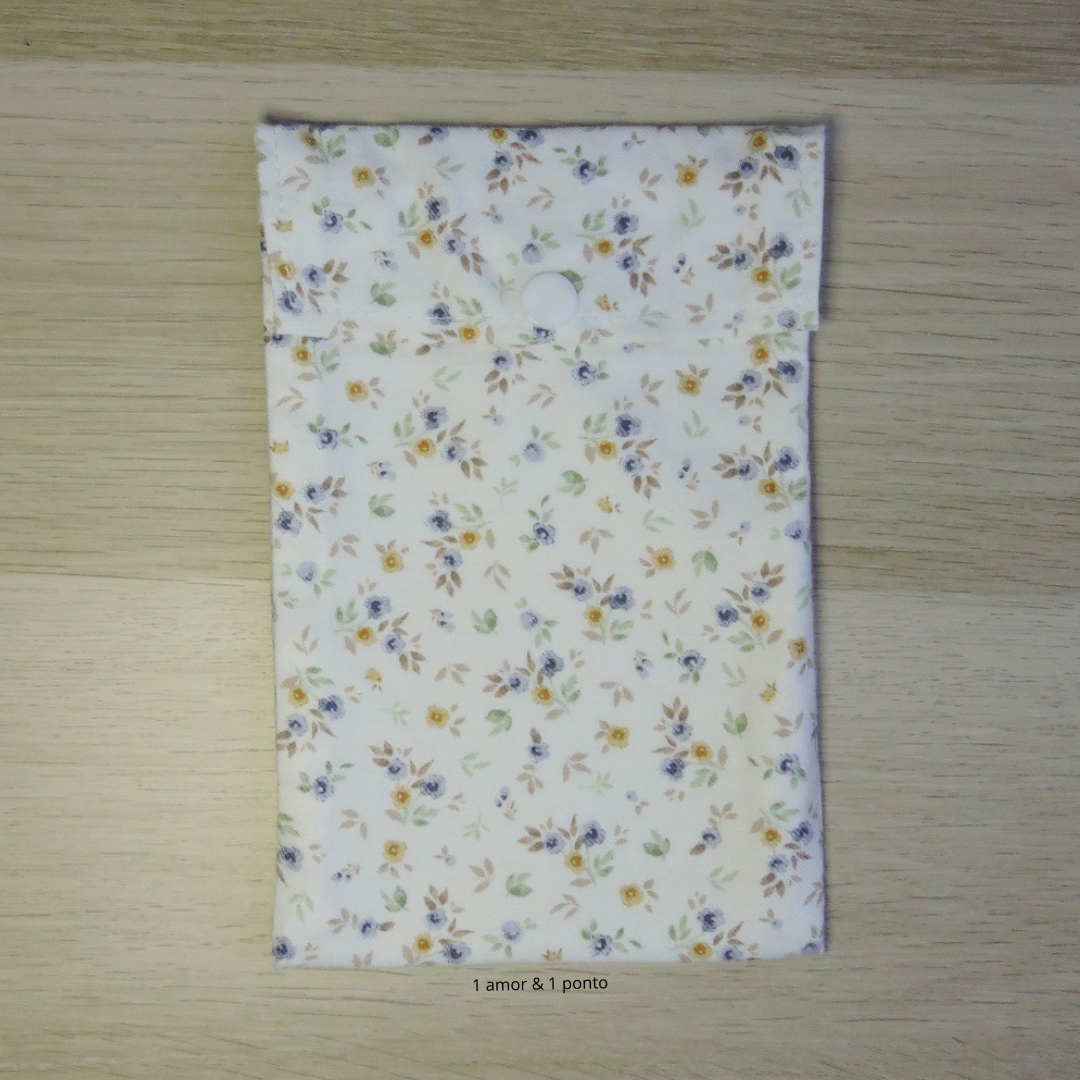 Bolsa de tecido floral com fecho branco sobre madeira clara