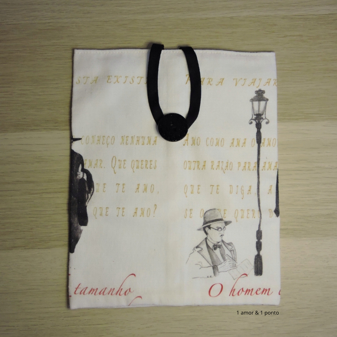 Estojo de tecido branco com texto em português e ilustrações em preto e amarelo, com fecho de fita preta e botão.