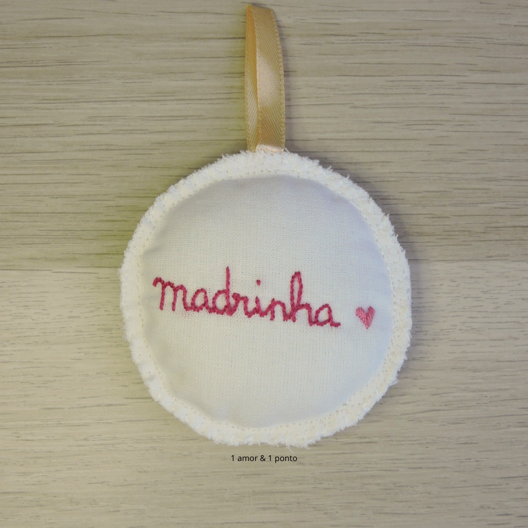 Ornamento redondo com bordado 'madrinha' e coração vermelho pendurado por fita dourada