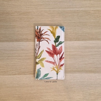 Carteira fina estampada com folhas coloridas sobre madeira clara