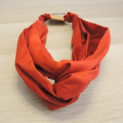Faixa de cabelo em tecido laranja com parte torcida e elástico
