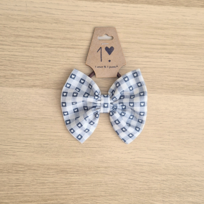 Laço de tecido branco com padrão azul em cartão castanho sobre madeira clara