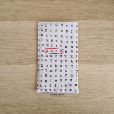 Tecido branco com letras pretas e palavra AMOR circulada a vermelho