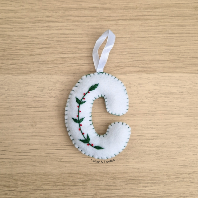 Enfeite em feltro branco na forma da letra C com bordado de folhas verdes e pontos vermelhos