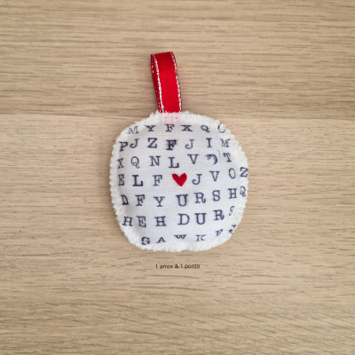 Alfineteiro de tecido branco com letras pretas e coração vermelho