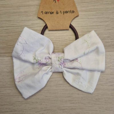 Elástico de cabelo com laço branco em tecido floral sobre cartão com etiqueta