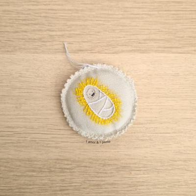 Patch bordado redondo com bebé em manta branca e detalhes amarelos