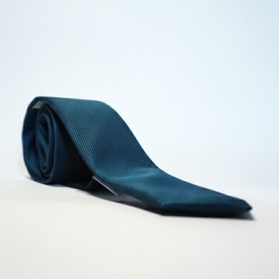 Gravata azul escura texturizada enrolada sobre superfície branca