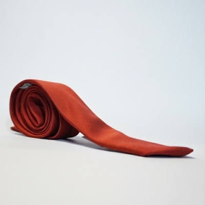 Gravata vermelha tijolo enrolada sobre fundo branco