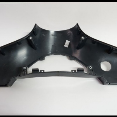 Peça plástica preta de automóvel com etiqueta branca sobre fundo branco